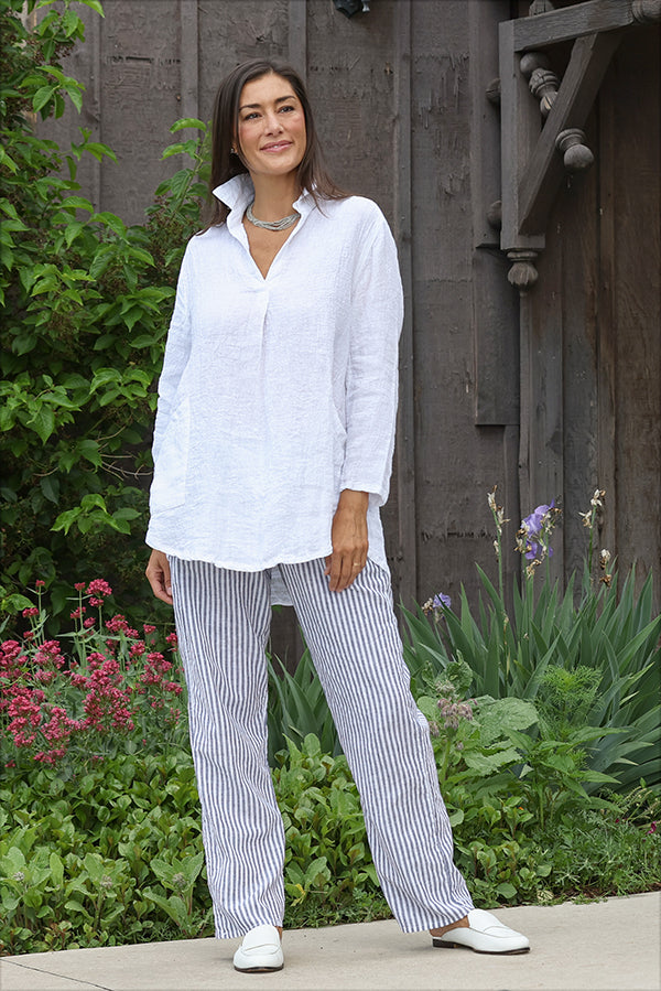 Woman wearing a white shirt and striped pants standing in a garden.