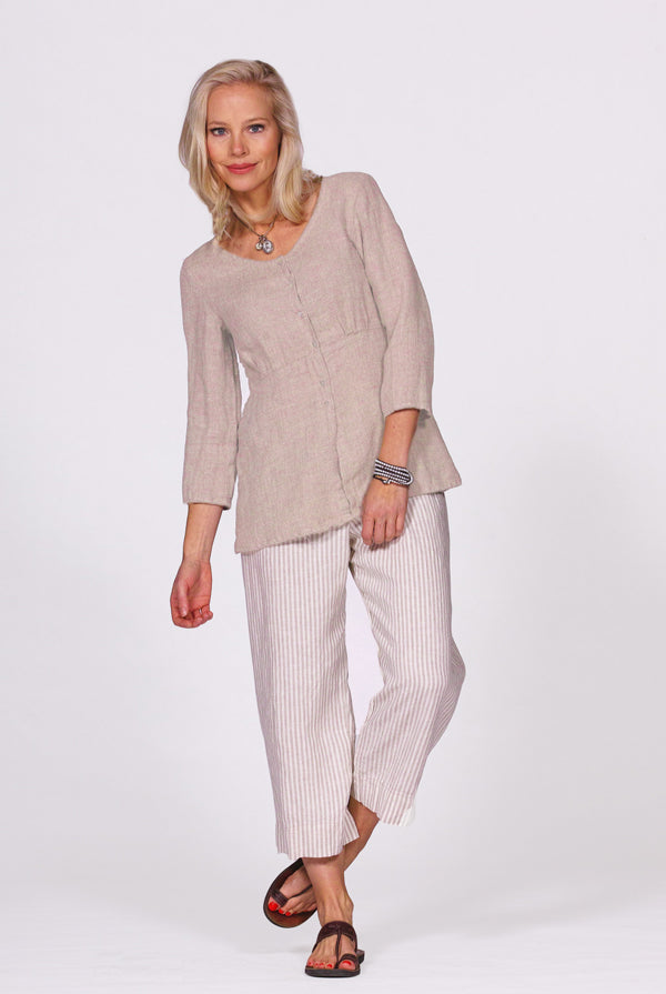 Woman wearing a beige top and white striped pants on a white background