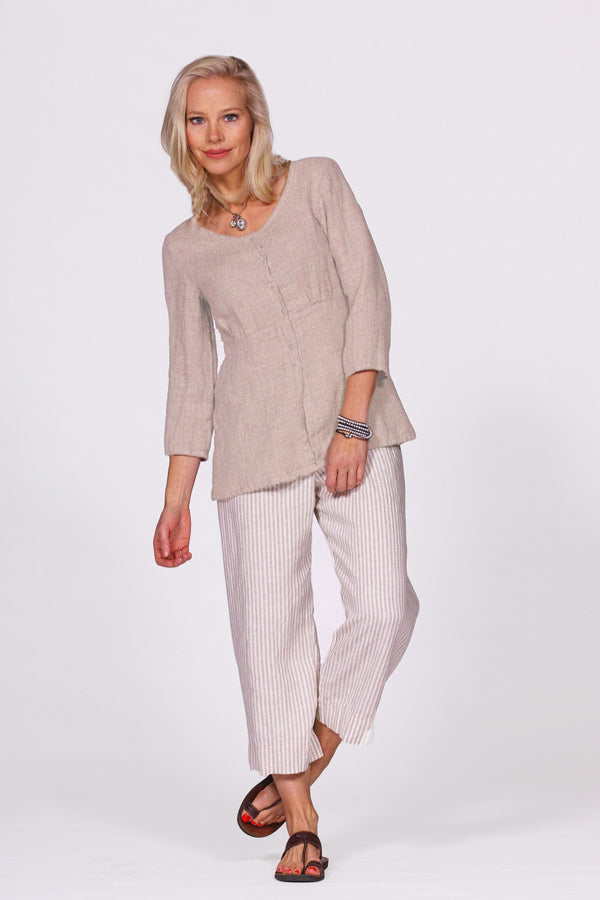 Woman wearing a beige top and white striped pants on a white background