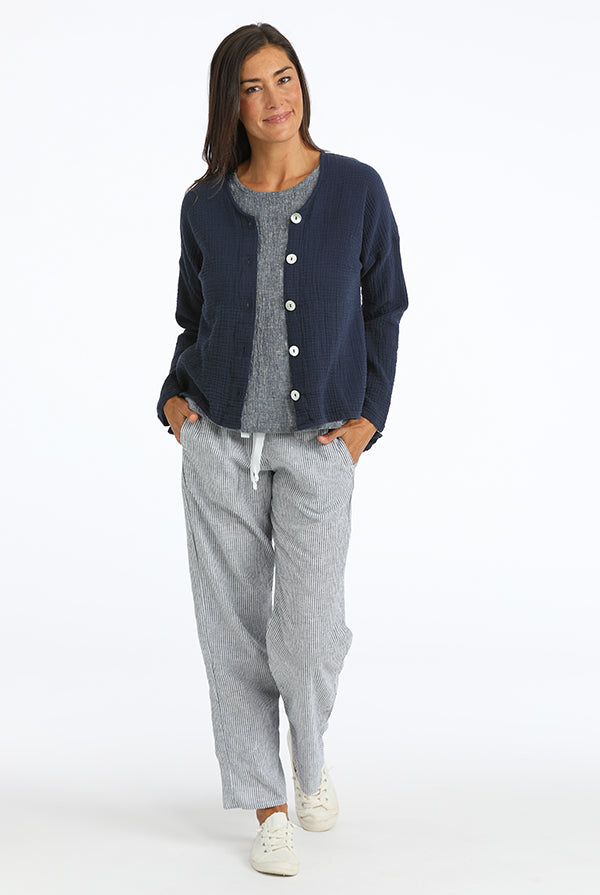 Woman wearing a navy cardigan over a gray shirt with gray pants on a white background