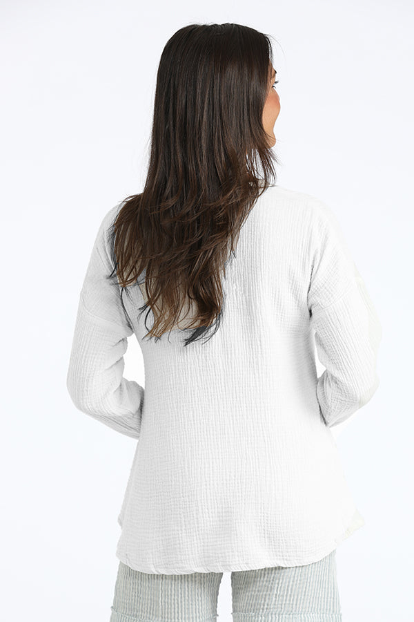 Woman wearing a white long-sleeve top with a subtle pattern on a white background