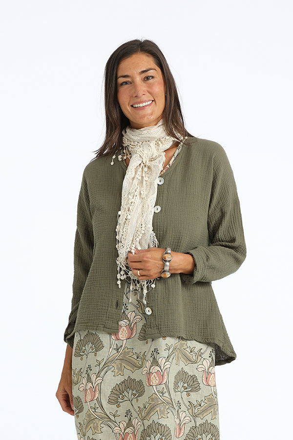 Woman wearing a green cardigan, floral skirt, and beige scarf on a white background