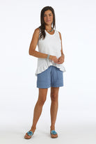 Woman wearing a white sleeveless top and blue shorts on a white background