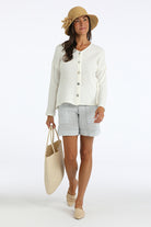 Woman wearing an ivory organic cotton gauze top and blue and white striped organic cotton shorts on a white background
