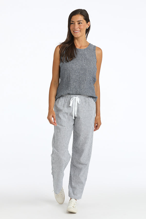 Woman wearing a gray sleeveless top and striped linen  pants on a white background